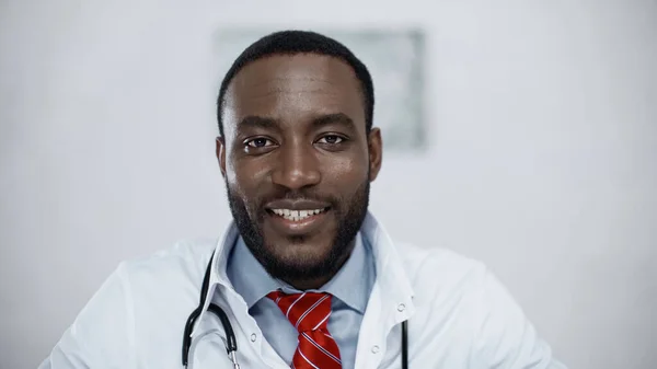 Médecin afro-américain positif en manteau blanc en clinique — Photo de stock