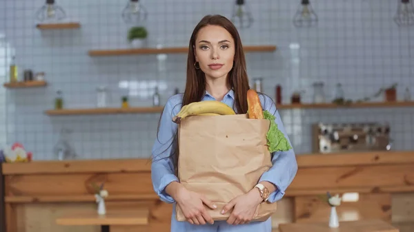 Brünette Frau hält Paket mit Lebensmitteln zu Hause — Stockfoto