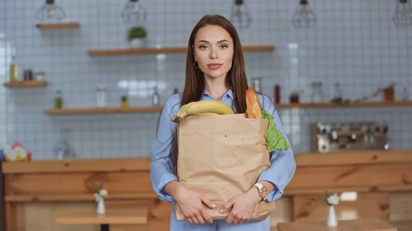 Morena mulher segurando pacote com comida em casa — Fotografia de Stock