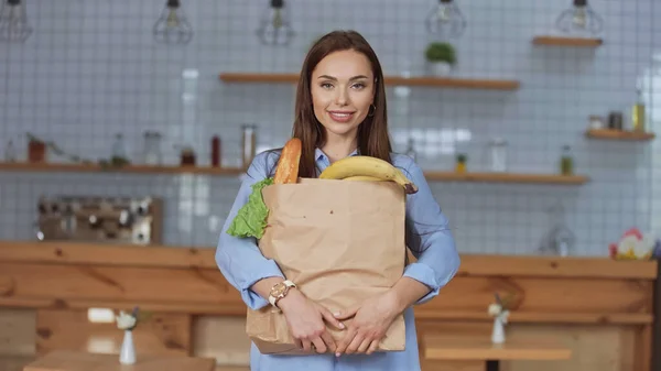 Sorrindo mulher segurando pacote com comida em casa — Fotografia de Stock