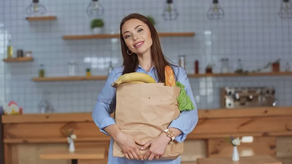 Positive Frau hält Paket mit Lebensmitteln zu Hause — Stockfoto