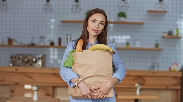 Mulher morena bonita segurando pacote com comida em casa — Fotografia de Stock