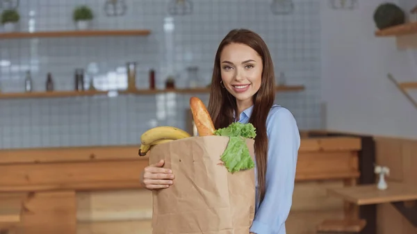 Feliz mulher segurando pacote com comida em casa — Fotografia de Stock