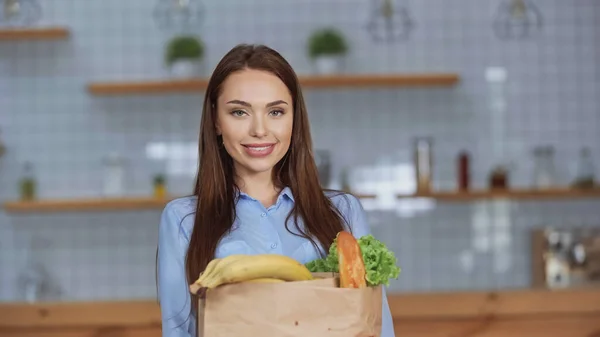 Mujer sonriente sosteniendo el paquete con comida en casa - foto de stock