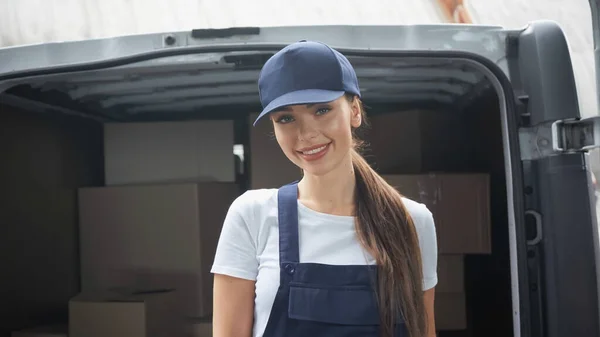 Mujer entrega feliz sonriendo a la cámara cerca del coche con paquetes al aire libre - foto de stock