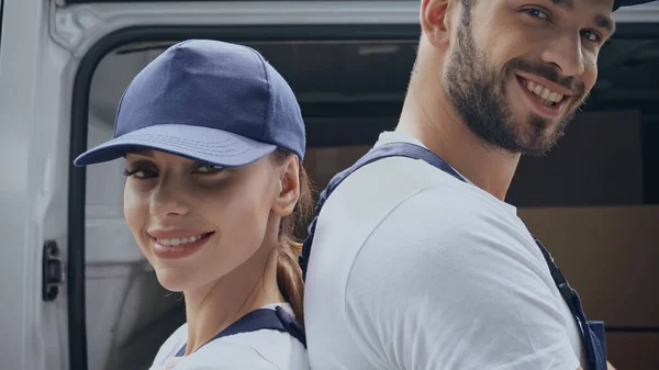 Positive couriers looking at camera near car outdoors — Stock Photo