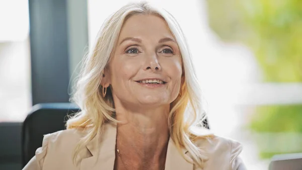 Blonde middle aged businesswoman smiling in office — Stock Photo