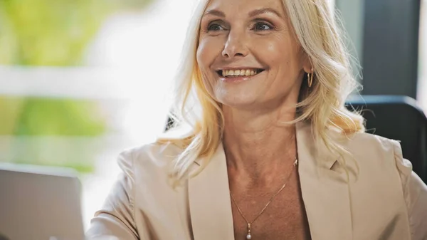 Joyeuse femme d'affaires d'âge moyen regardant loin dans le bureau — Photo de stock