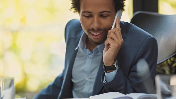 Positivo uomo d'affari afroamericano che parla al cellulare in ufficio — Foto stock