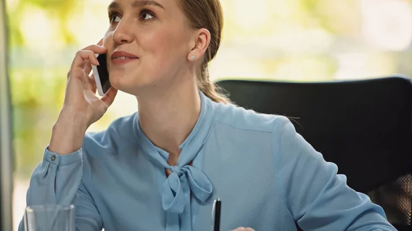Радостная деловая женщина смотрит в сторону, разговаривая по мобильному телефону в офисе — стоковое фото