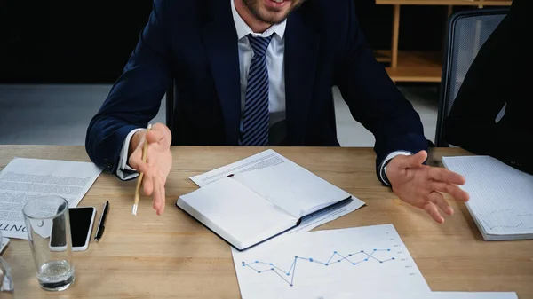 Partial view of businessman gesturing near empty notebook and documents in office — Stock Photo