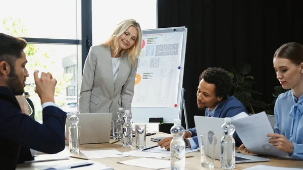 African american man pointing with pen at document during business meeting with colleagues — Stock Photo