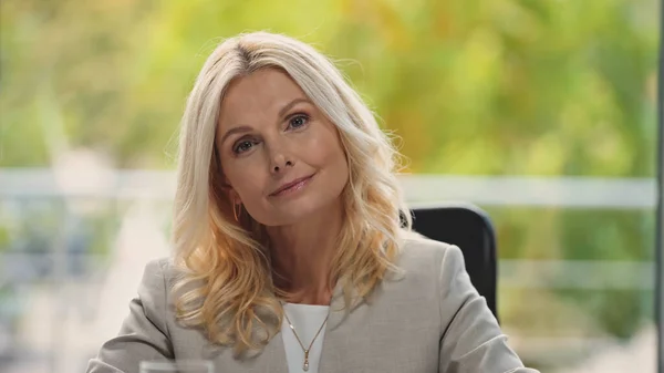 Positive middle aged businesswoman looking at camera in office — Stock Photo