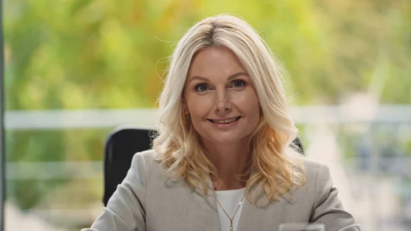 Blondine mittleren Alters lächelt im Büro in die Kamera — Stockfoto