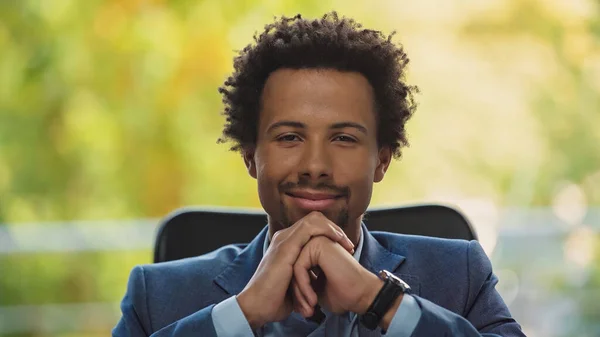 Joven y exitoso empresario afroamericano sonriendo a la cámara en la oficina - foto de stock