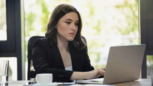 Konzentrierte Geschäftsfrau tippt am Arbeitsplatz am Laptop — Stockfoto