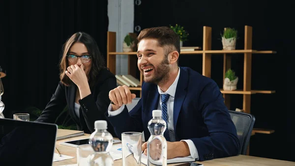 Excited businessman laughing near woman in eyeglasses in office — Stock Photo