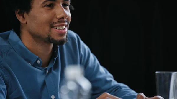 Heureux homme d'affaires afro-américain souriant au bureau sur le premier plan flou — Photo de stock