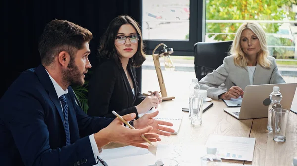 Young manager pointing with hands while talking to colleagues during business meeting — Stock Photo