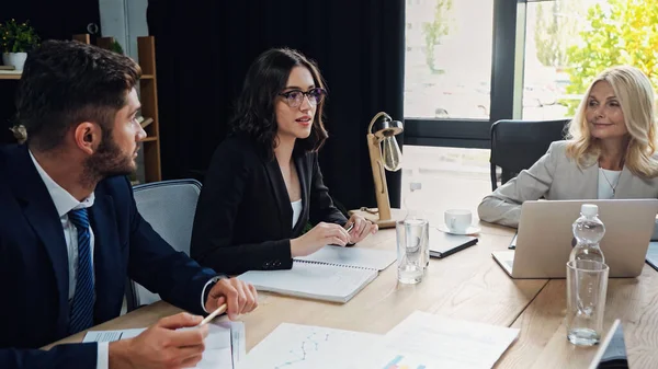 Partenaires d'affaires regardant femme dans les lunettes parler pendant la réunion — Photo de stock