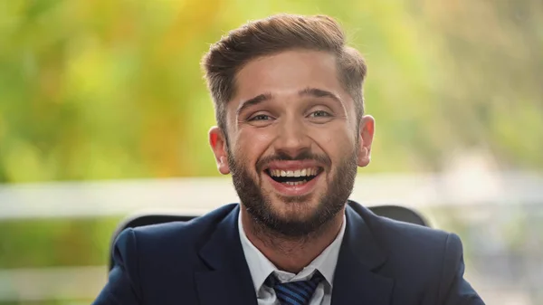 Der junge und gut gelaunte Geschäftsmann lacht im Büro vor laufender Kamera — Stockfoto