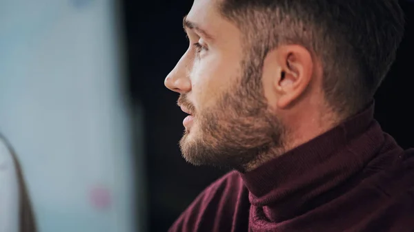 Profile of young bearded businessman in turtleneck on blurred background — Stock Photo