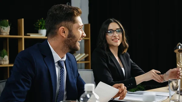 Young businessman laughing near smiling woman in eyeglasses in meeting room — Stock Photo