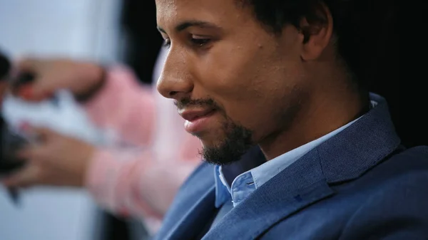 Close up vista do jovem empresário afro-americano sorrindo em fundo borrado — Fotografia de Stock