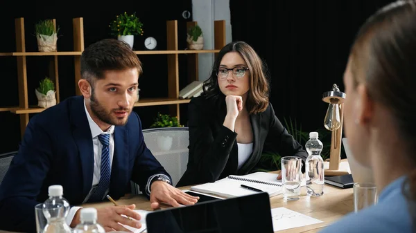 Joven hombre de negocios hablando con colegas durante la reunión en el cargo - foto de stock