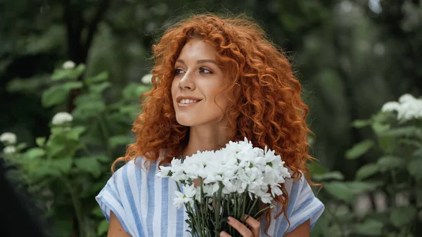 Donna rossa felice che tiene mazzo di fiori bianchi — Foto stock
