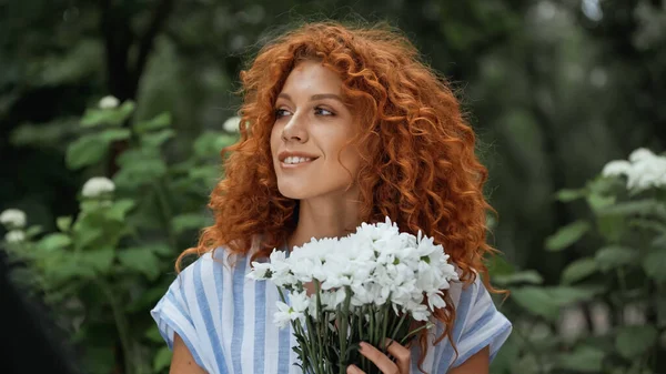 Mujer pelirroja feliz sosteniendo ramo de flores blancas - foto de stock