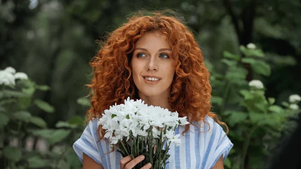 Donna rossa allegra che tiene il mazzo di fiori bianchi — Foto stock