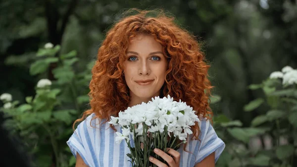 Довольная рыжая женщина с букетом белых цветов — стоковое фото