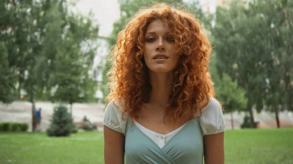 Jolie rousse femme regardant caméra dans le parc — Photo de stock