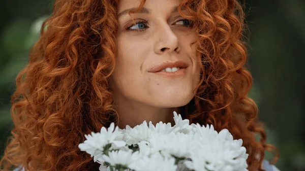 Primer plano de mujer pelirroja feliz cerca de flores blancas - foto de stock