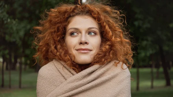 Heureux rousse femme avec les yeux bleus couverts de couverture à l'extérieur — Photo de stock