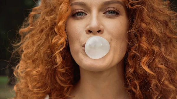 Close up view of curly woman blowing bubble gum — Stock Photo