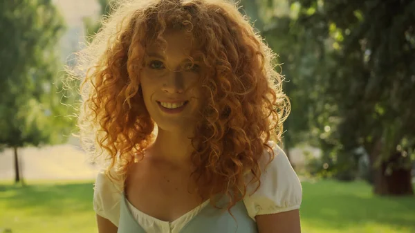 Soleil sur les cheveux bouclés de la femme souriant dans le parc — Photo de stock