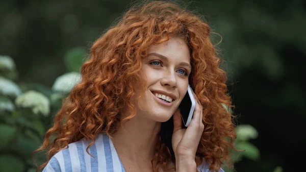 Felice giovane donna con i capelli rossi parlando su smartphone — Foto stock