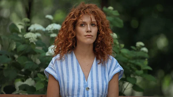 Mécontent jeune rousse femme en robe rayée en attente dans le parc — Photo de stock