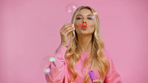 Jolie femme soufflant des bulles de savon isolées sur rose — Photo de stock