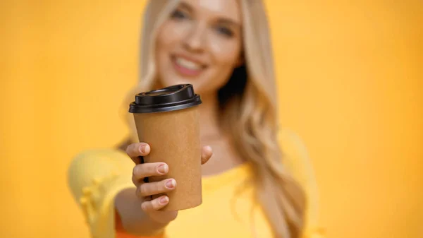 Kaffee to go in der Hand einer verschwommenen Frau isoliert auf gelb — Stockfoto