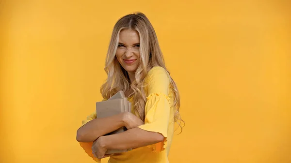 Happy blonde woman holding books isolated on yellow — Stock Photo