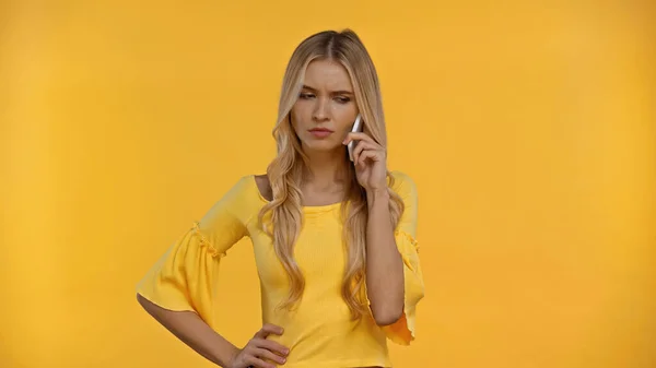 Сумна блондинка говорить на смартфоні ізольовано на жовтому — стокове фото