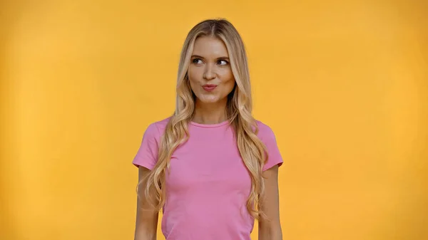 Sly blonde woman in t-shirt looking away isolated on yellow — Stock Photo