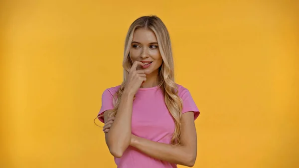 Tricky woman holding finger near mouth isolated on yellow — Stock Photo