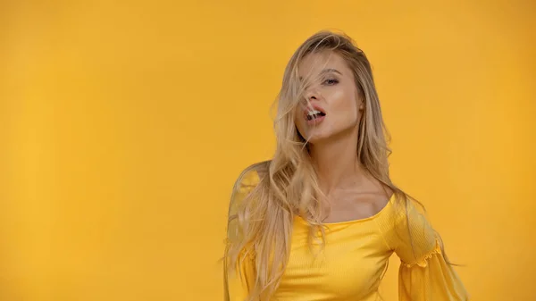 Mujer rubia en blusa posando aislada en amarillo - foto de stock