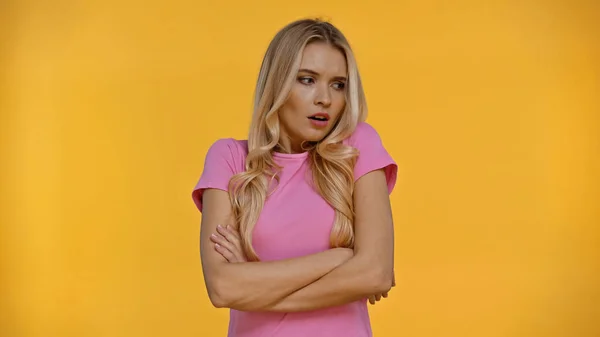 Embarrassed blonde woman crossing arms isolated on yellow — Stock Photo