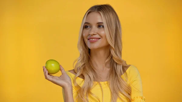 Cheerful woman holding fresh green apple isolated on yellow — Stock Photo