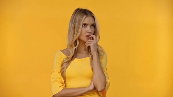 Mujer reflexiva en blusa mirando hacia otro lado aislado en amarillo - foto de stock